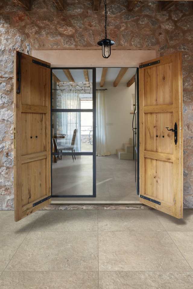 natural stone tile on outdoor patio leading into rustic home with old wooden doors and stonework